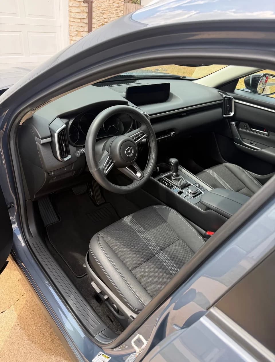 Dark Mazda cabin showing dashboard, center console and cloth front seat