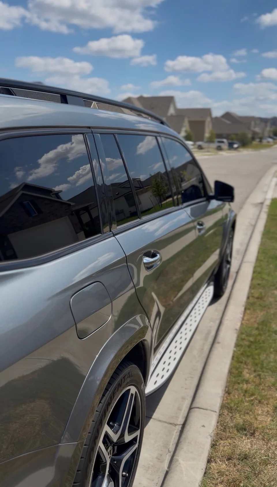 Reflections in the side panels and windows of a gray Mercedes SUV