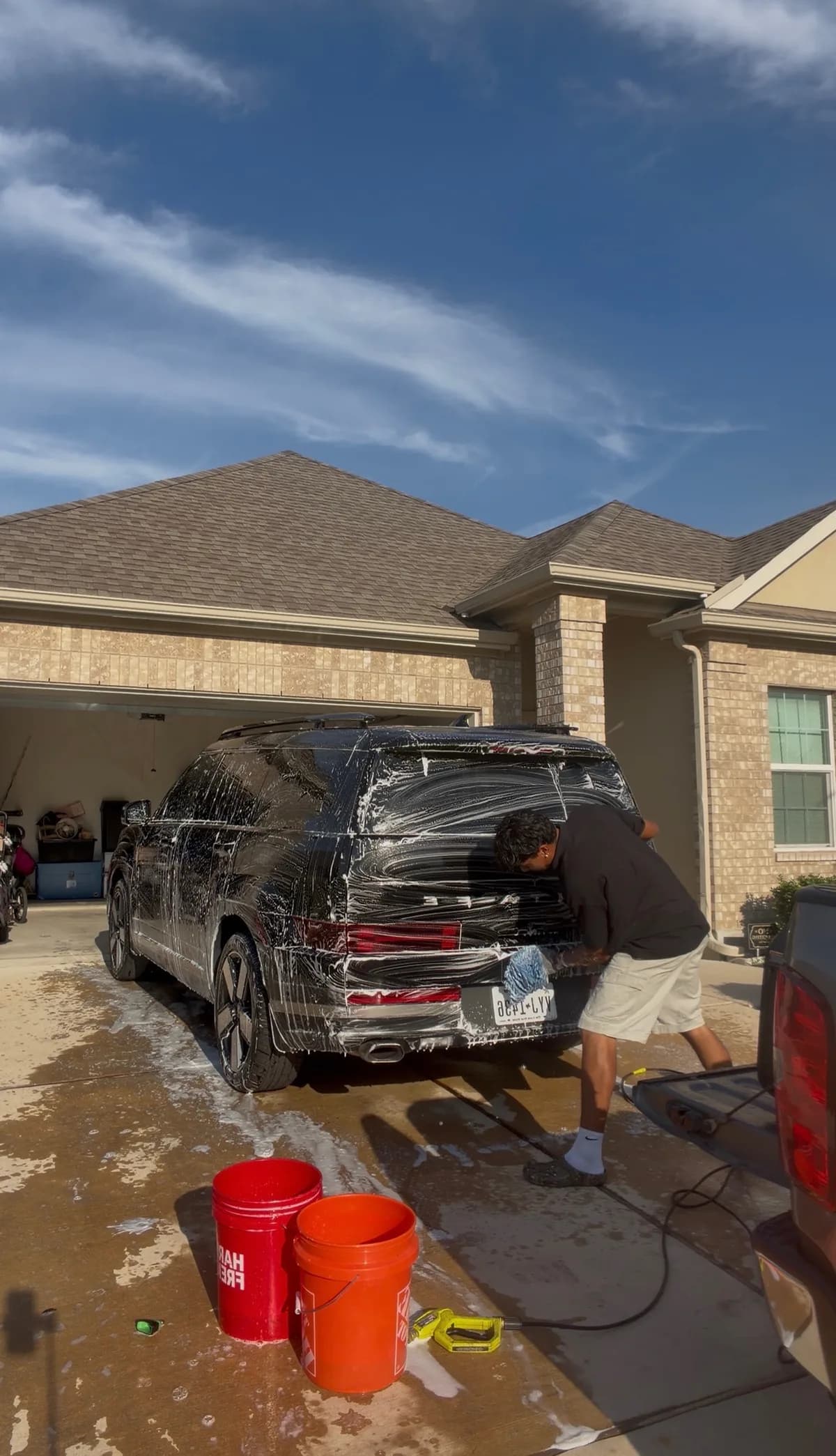 The owner hand washing the back of a black SUV with a wash mitt